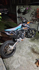 Motorcycle parked on a stone surface with a building and plants in the background