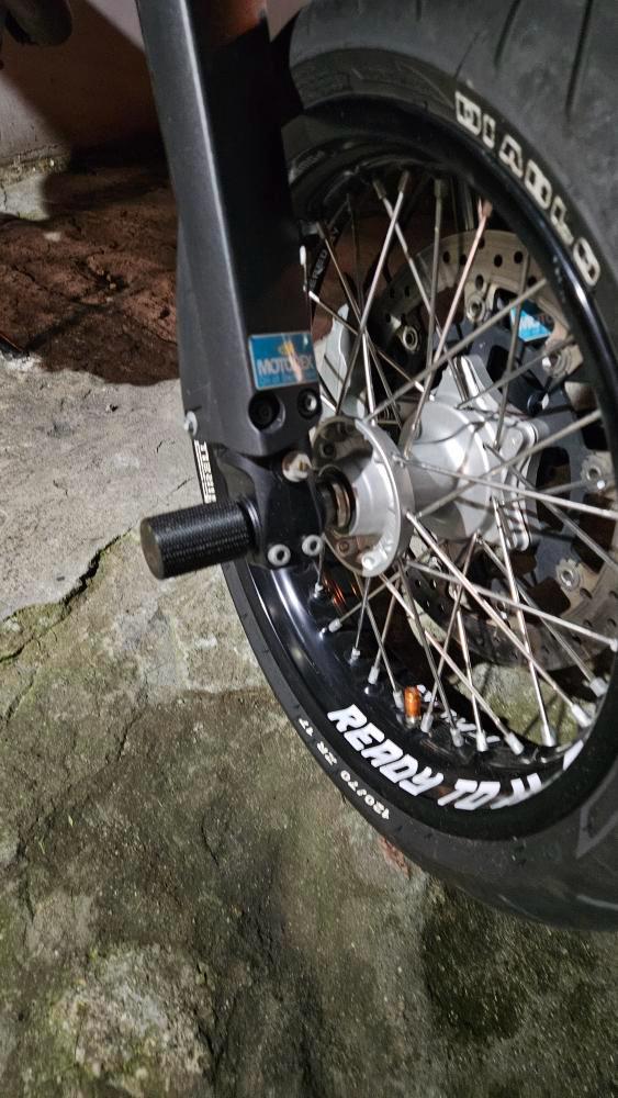 Close-up of a motorcycle wheel with a visible brand logo on a concrete surface.