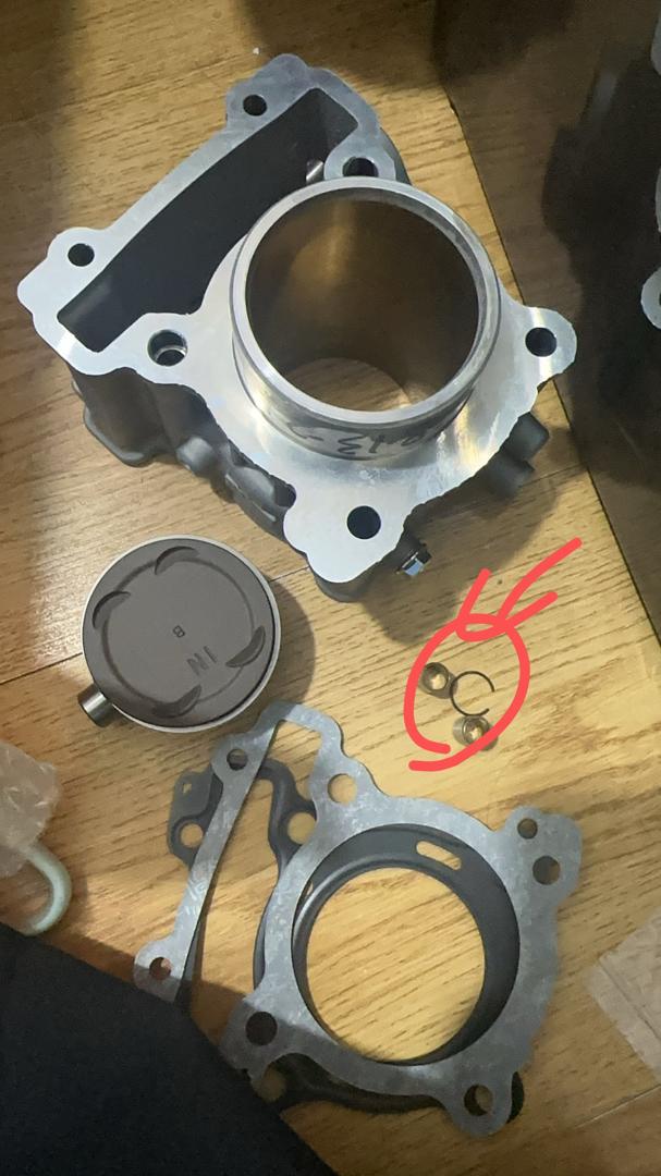 Mechanical parts on a wooden surface with red annotations.