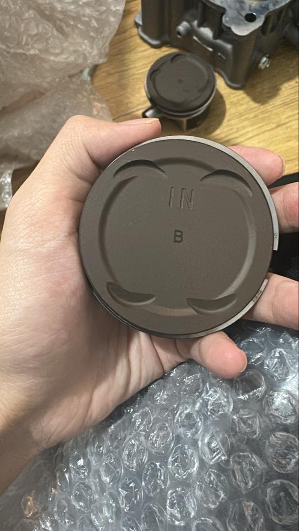 Hand holding a brown circular object with 'B' branding, on a blurred background